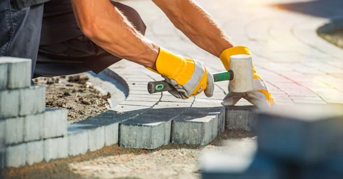 strong person wearing gloves and installing patio pavers in a circular pattern