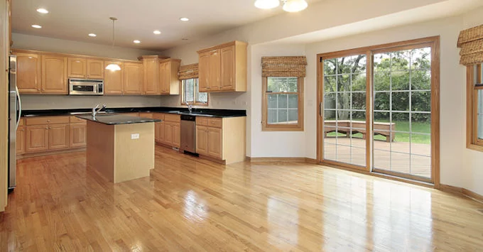 vacant home with wood flooring and open floor plan featuring kitchen with wooden cabinets and french doors