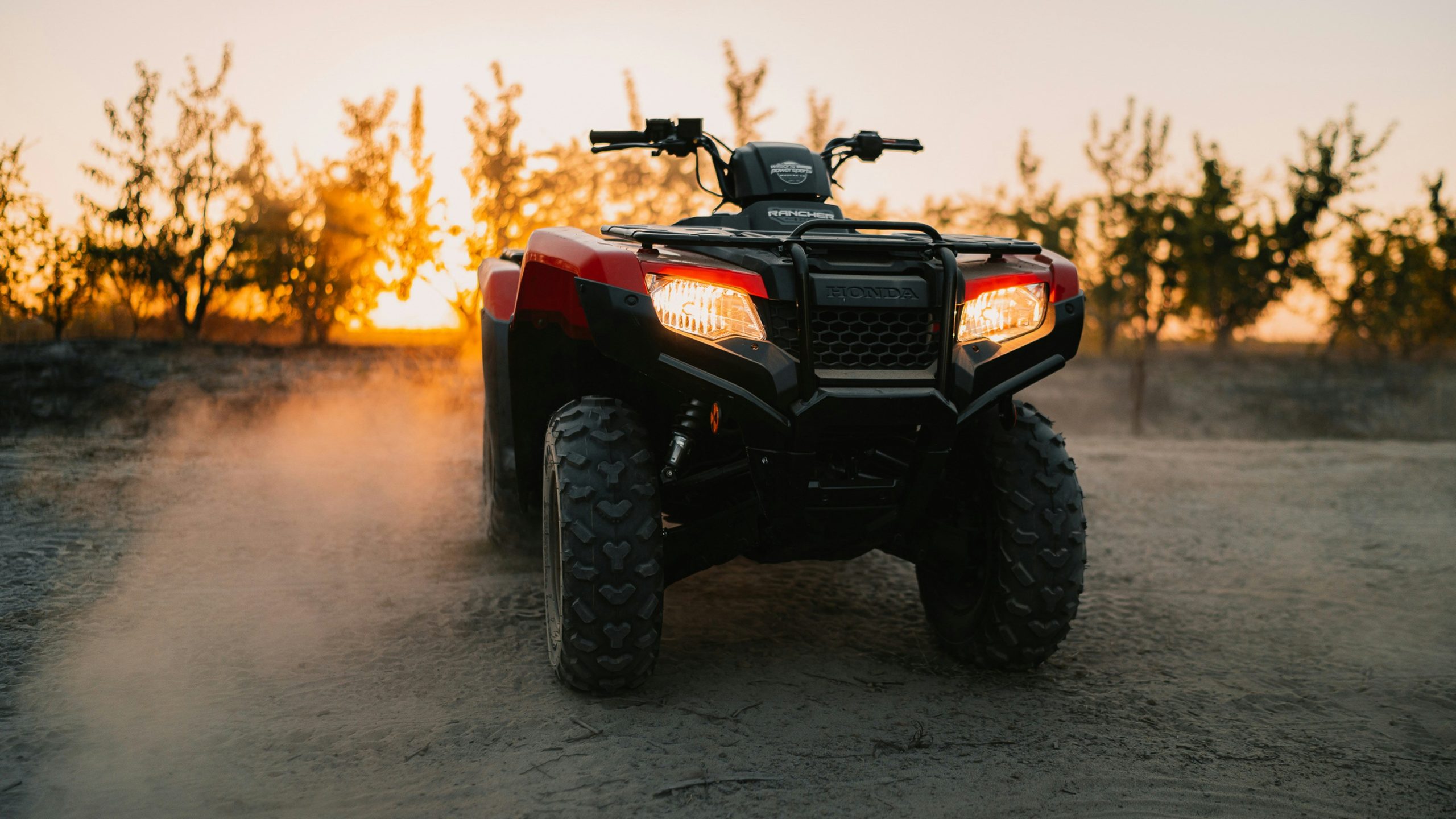 atv with dust blowing around as the sun sets in the background
