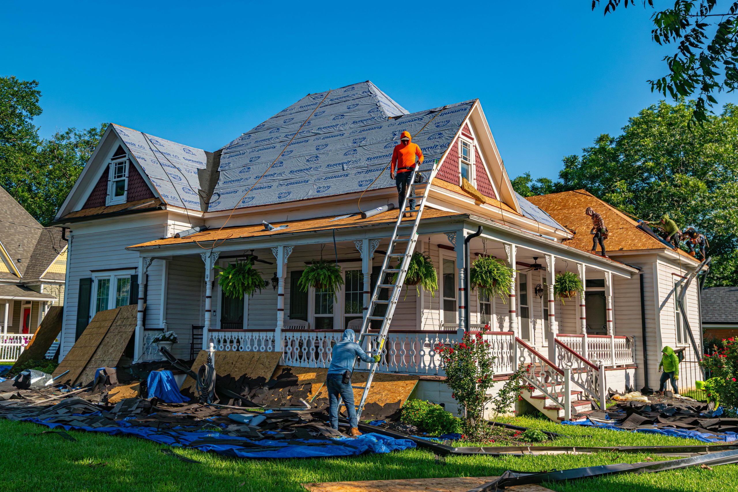 a home in Texas that is under construction, workers setting up a ladder and prepping to finish the roof with new shingles